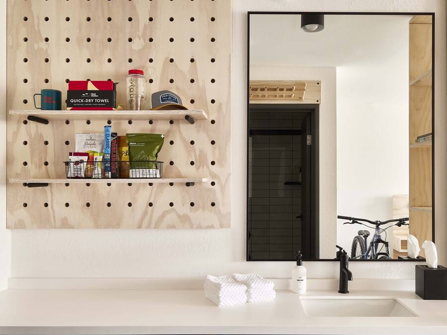 Un baño con pared de tablero de madera, un espejo grande y un lavabo blanco.