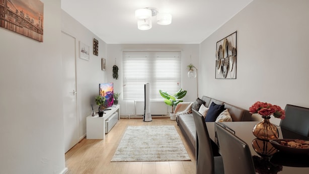 Ett modernt vardagsrum med en platt-TV, en soffa, ett soffbord och en krukväxt.