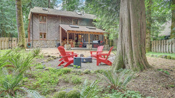 A rustic cabin with a covered patio, red Adirondack chairs, and a fire pit. - Mt. Hood Alpine Chalet w/ hot tub, kid & dog friendly (Rhododendron)