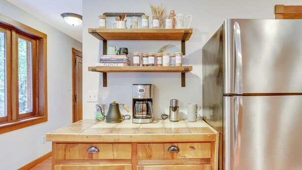 Una cocina con armarios de madera, un refrigerador de acero inoxidable y una cafetera sobre la encimera.