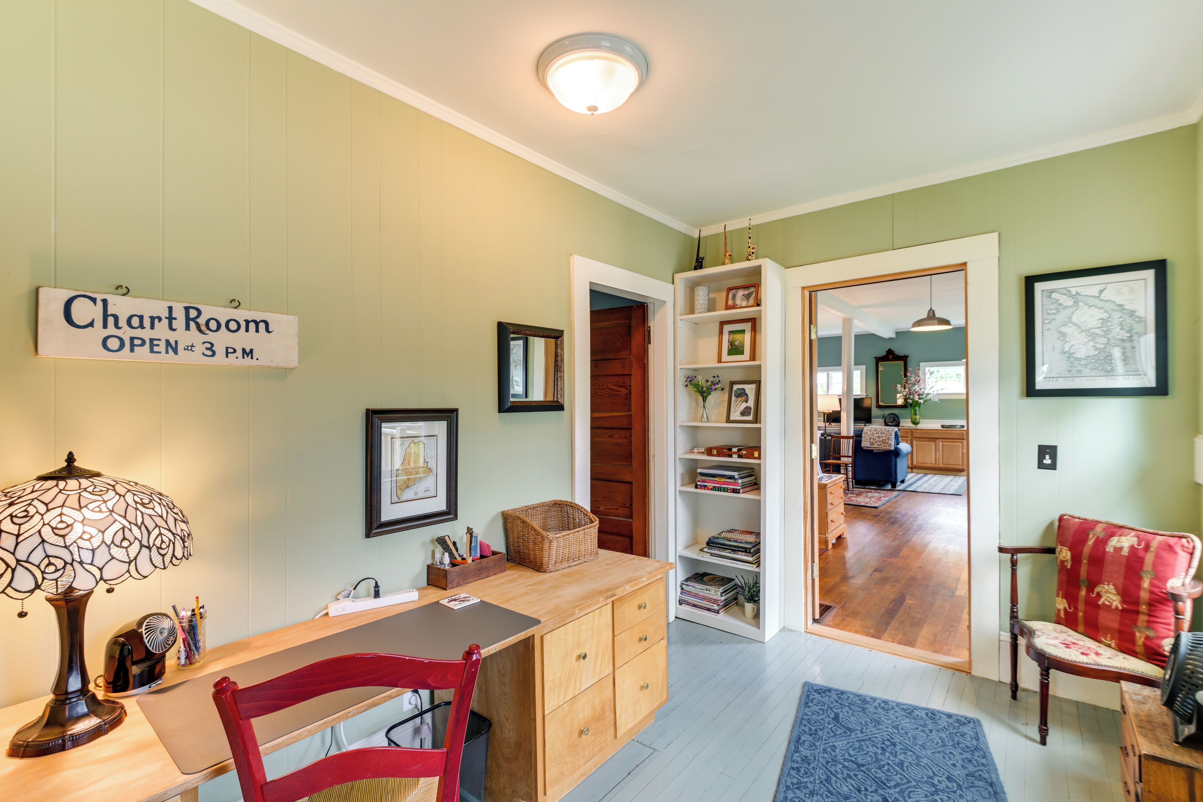 A room with a desk, chair, lamp, and a sign indicating the chart room is open at 3 PM.
