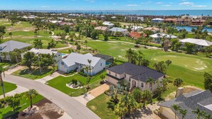 Un barrio residencial con casas, un campo de golf y una masa de agua al fondo.