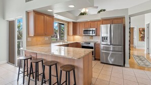 Una cocina moderna con armarios de madera, electrodomésticos de acero inoxidable y una isla grande con taburetes.