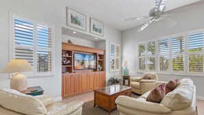 Una sala de estar con un sofá color beige, una mesa de centro de madera y un mueble de televisión con armarios.