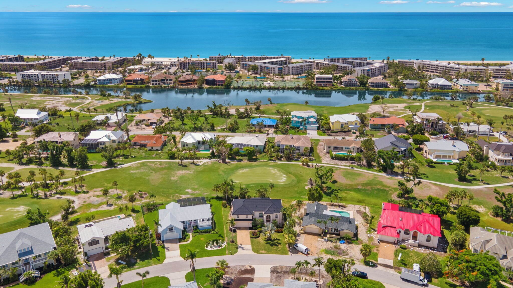 An aerial view of a coastal resort with multiple buildings, a golf course, and a large body of water.