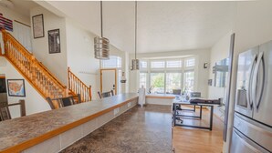 A kitchen with a granite countertop, stainless steel appliances, a wooden staircase, and large windows. - Family & Business • Minutes to Spokane Airport, • Fairchild AFB & Northern Quest (Spokane)