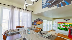 A dining area with a table set for two, a television, and artwork on the walls. - Family & Business • Minutes to Spokane Airport, • Fairchild AFB & Northern Quest (Spokane)