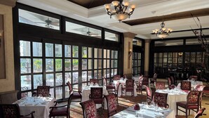 Un comedor espacioso con ventanas amplias, candelabros elegantes y muebles clásicos.
