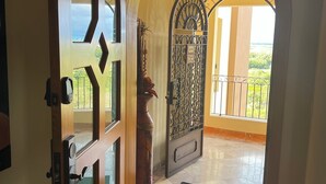 Un pasillo con una puerta de madera, un portón metálico y vistas a un balcón.