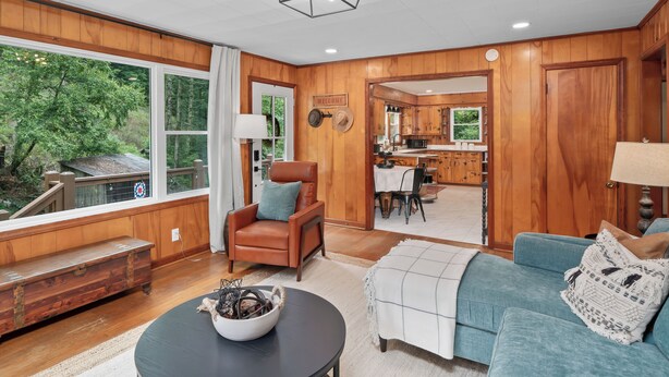 A spacious living room with a large window, a cozy fireplace, and a view of the outdoors. - Charming Mtn Cabin, Hot Tub+Fire Pit, Private, WiFi, Grill, Near Green Mtn Area! (Green Mountain)