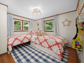 A bedroom with two beds, a checkered rug, a chandelier, and a basketball hoop. - Ray's Mtn Retreat ~ Hot Tub+Fire Pit, WiFi, Grill! (Green Mountain)