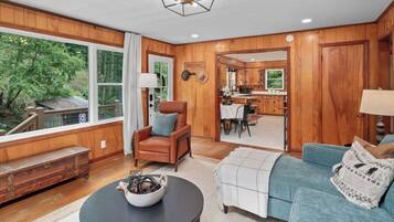 A spacious living room with a fireplace, a sofa, a coffee table, and a view of the outdoors.