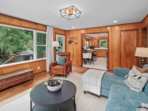 A spacious living room with a fireplace, a sofa, a coffee table, and a view of the outdoors.