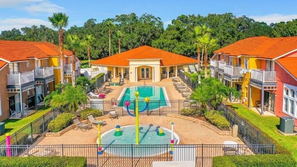 A resort with multiple buildings, a central pool area, and surrounding greenery. - Modern Disney Retreat! 2 Pools + Prime location (Kissimmee)
