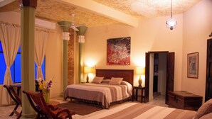 Ein Hotelzimmer mit einem großen Bett, zwei Nachttischlampen, einem Holznachttisch, einer Holzkommode und einem Gemälde an der Wand.