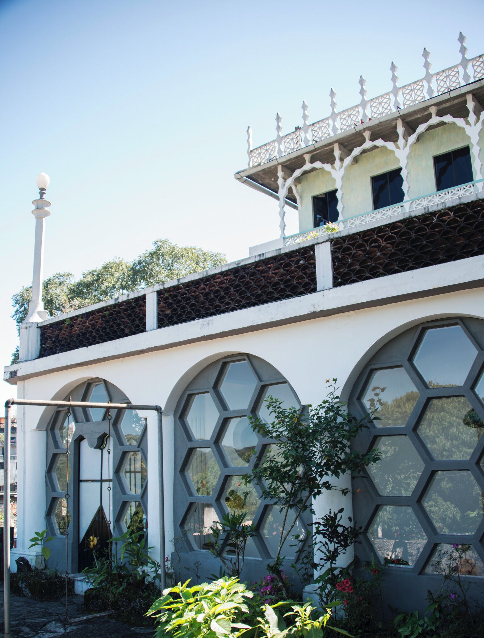 A building with a white facade, large hexagonal windows, and a decorative balcony with a lattice design.