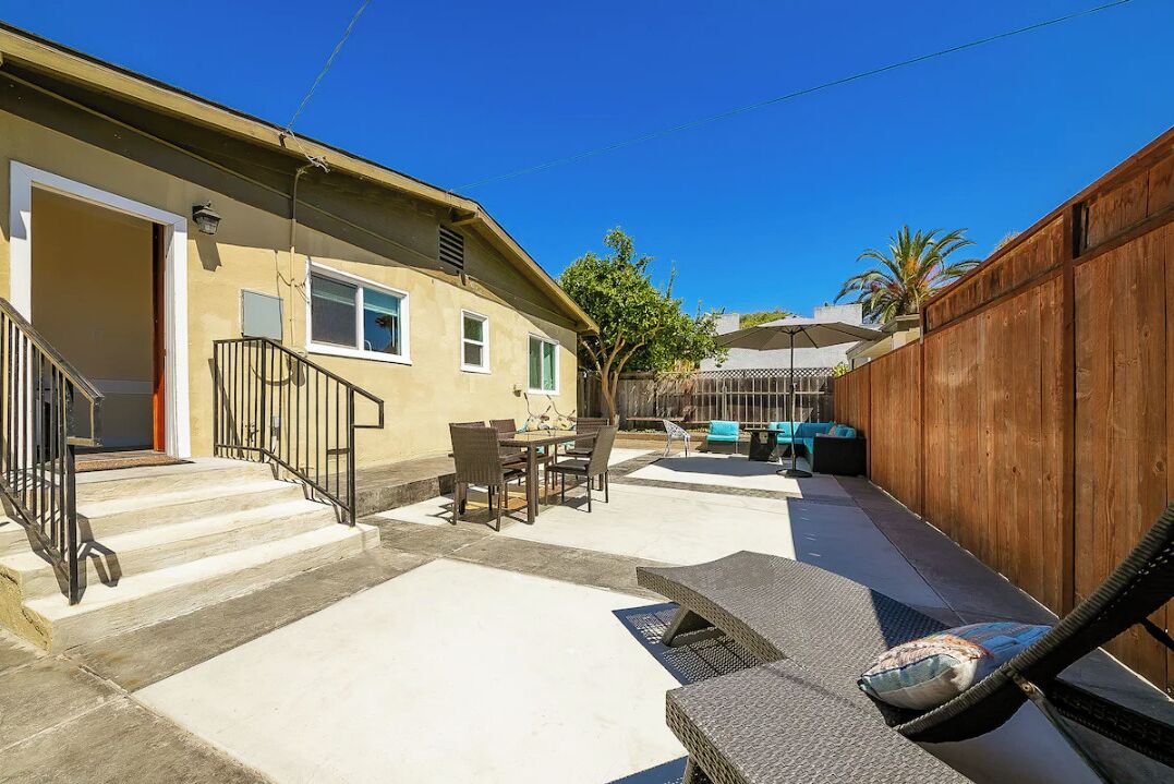 A residential backyard with a patio, outdoor furniture, and a wooden fence.