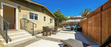 A residential backyard with a patio, outdoor furniture, and a wooden fence.