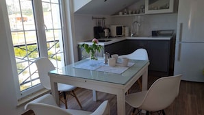 Een moderne keuken met witte kastjes, een glazen eettafel en witte stoelen.