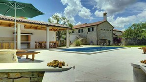 A pool area with a stone house, outdoor seating, and a covered patio. - Villa with pool and volleyball court (Barban)