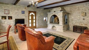A stone-walled living room with a fireplace, leather sofas, and a television. - Villa with pool and volleyball court (Barban)