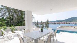 A terrace with a table and chairs, a small pool, and a view of a town and hills.