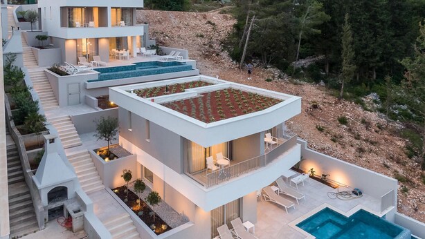 A modern multi-story house with a pool, outdoor seating, and a landscaped garden.