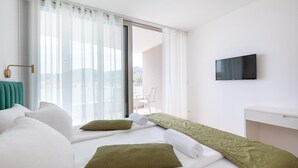 A modern hotel room with a large bed, a TV, and a balcony with a view.