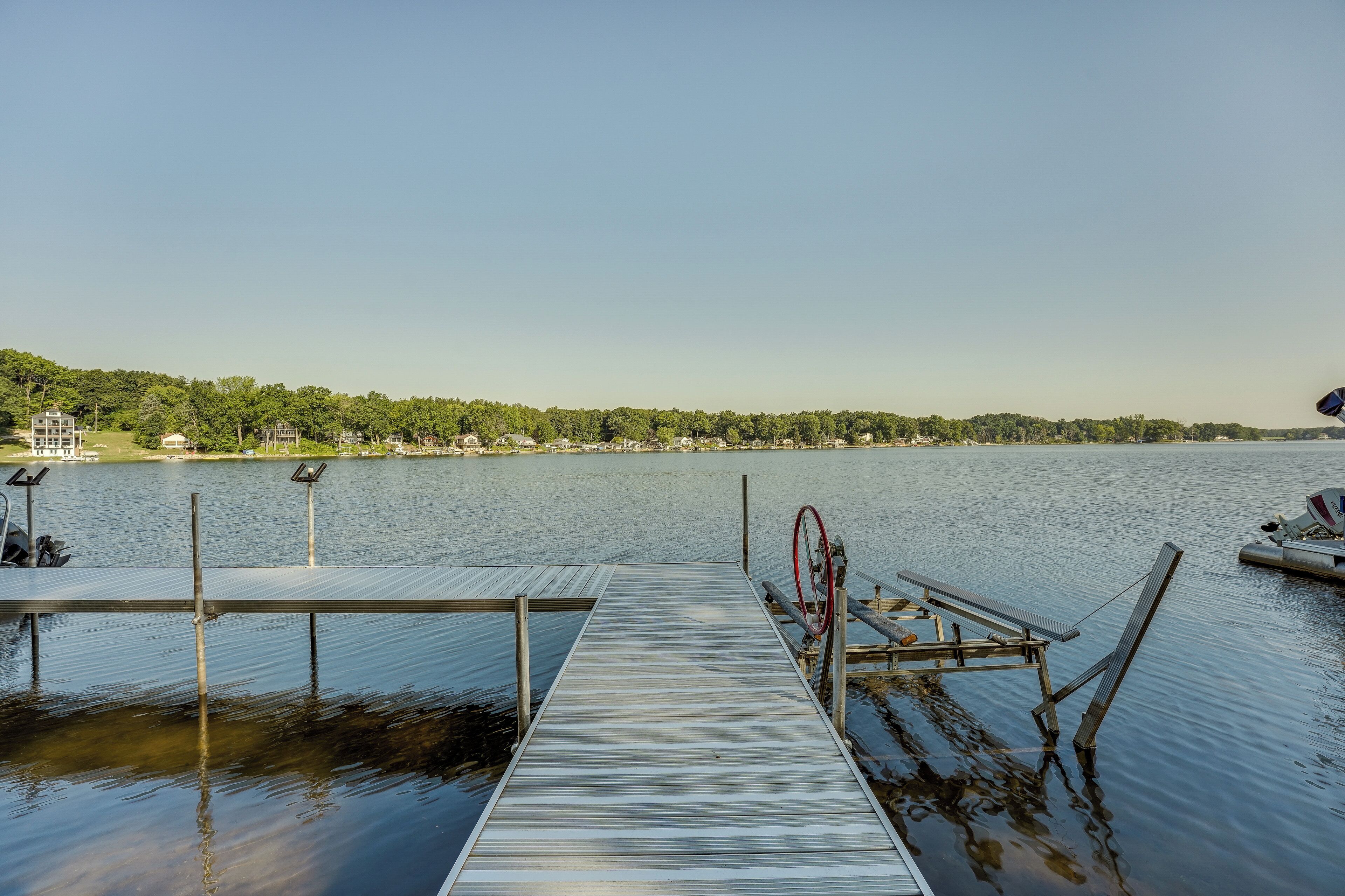 A wooden dock extending into calm water with a clear sky above.