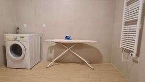 Un cuarto de lavandería con lavadora, tabla de planchar y radiador.