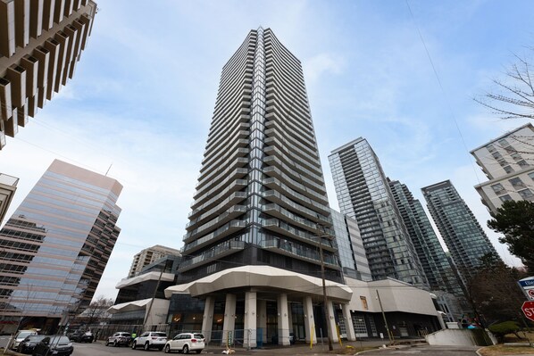 A tall, modern skyscraper with a unique angular design, surrounded by other high-rise buildings. - 28th floor luxury 1 bedroom 1 bathroom condo in heart of Toronto | sleep up to 4 (Toronto)
