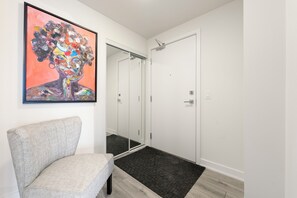 Une salle de bain moderne avec une chaise grise, un grand miroir et une douche.