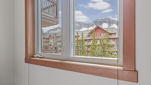 A window with a view of a mountain and houses. - Heated Pool, Hot Tubs, and Comfort for 6: Your Desired Canmore Escape! (Canmore)