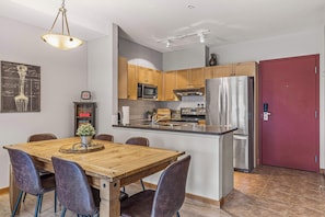 A modern kitchen with wooden cabinets, stainless steel appliances, and a red door.