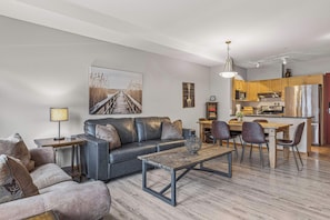 A modern living room with a sofa, coffee table, and dining area.