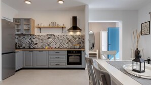 Eine moderne Küche mit grauen Schränken, einem eingebauten Ofen und einer gemusterten Spritzschutzwand.