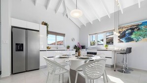 A modern kitchen with a central island, white cabinetry, and a large window overlooking a scenic view. - *NEW* Modern 3BR2BA Home w/ Private Pool & Patio (Oranjestad)