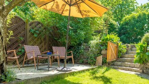 A patio with two wicker chairs, a small table, and a yellow umbrella.