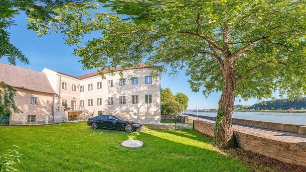 Un bâtiment à deux étages avec une allée pavée et une voiture garée.