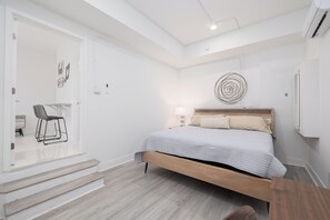 Relax in a serene bedroom with a large bed, a compact desk, and a unique wall-mounted artwork.