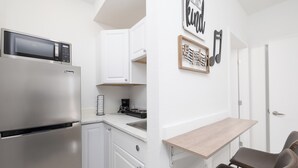 A compact kitchen with a built-in microwave, a coffee machine, and a sink. There is a small wooden table and two chairs. - Serenity Studio - Adorable 1 BR near Florida Keys (Florida City)