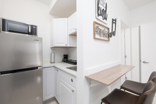 Compact kitchen with modern appliances, sink, and seating area.