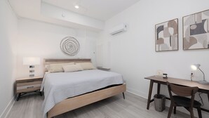 A modern bedroom with a bed, bedside table, desk, chair, and artwork. - Serenity Studio - Adorable 1 BR near Florida Keys (Florida City)