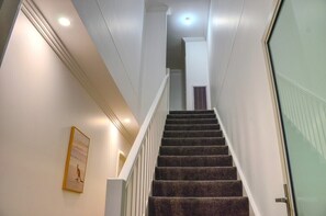 Stairs lead to an upper floor with a carpeted finish and white railing.