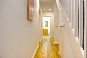 Stylish hallway leads to a clean and contemporary bathroom with a sink and mirror.