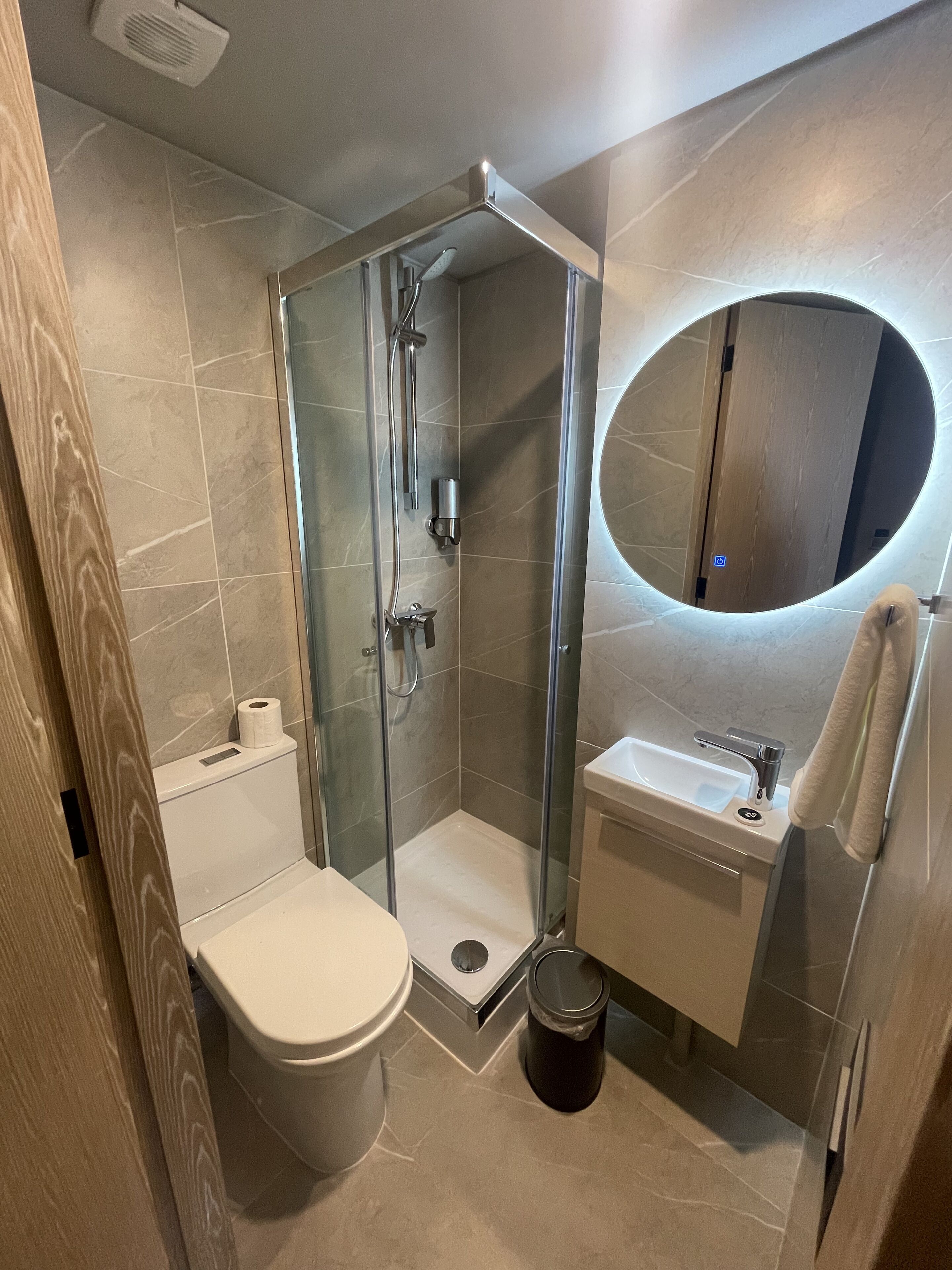 A modern bathroom with a glass-enclosed shower, a toilet, a sink, and a mirror.