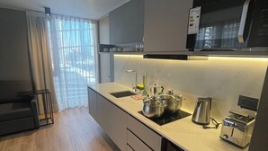 Eine moderne Küche mit Einbauherd, Kaffeemaschine und Toaster. Ein Fenster mit transparenten Vorhängen bietet Blick ins Freie.