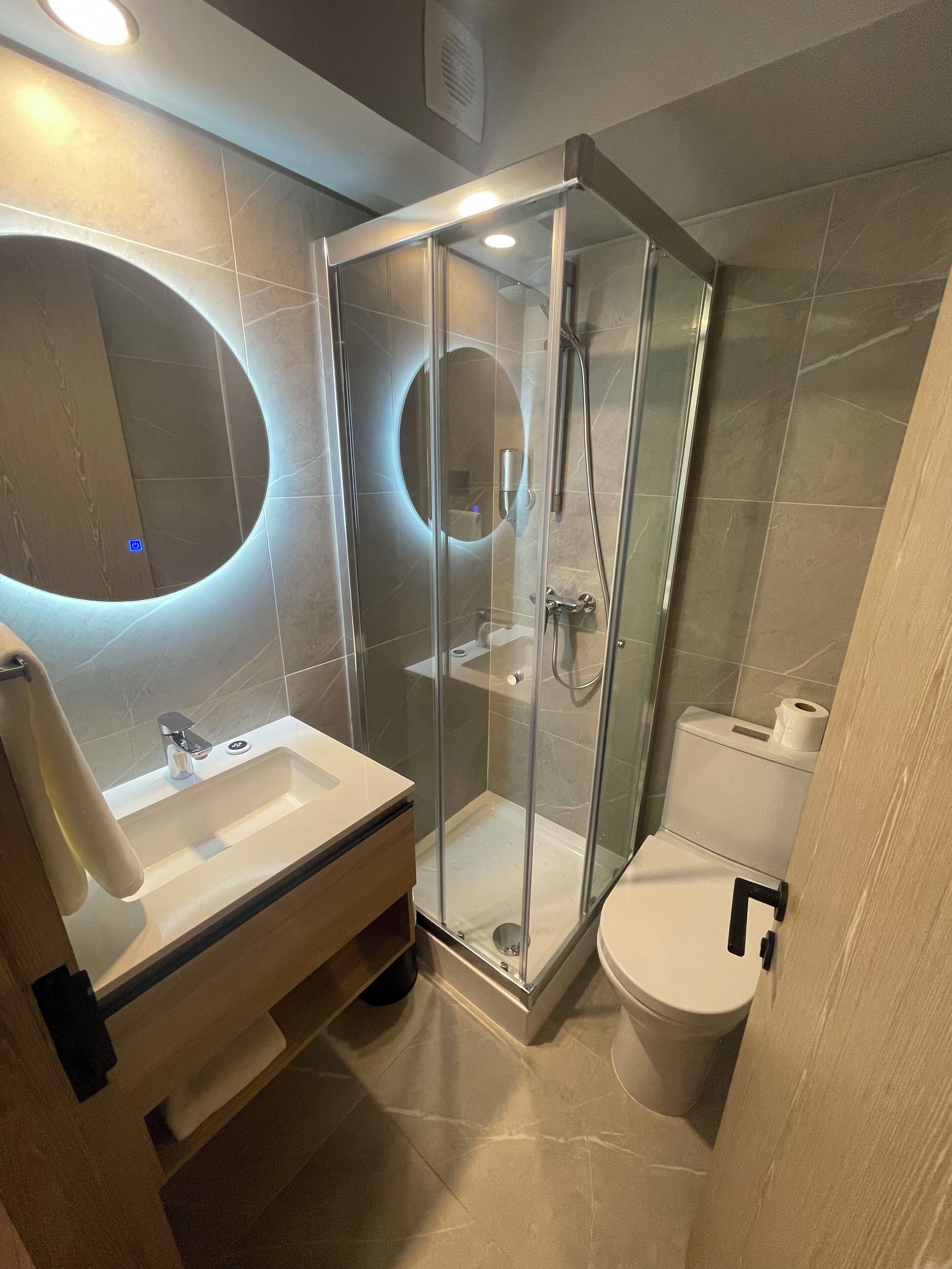 A modern bathroom with a glass-enclosed shower, a sink, and a toilet.