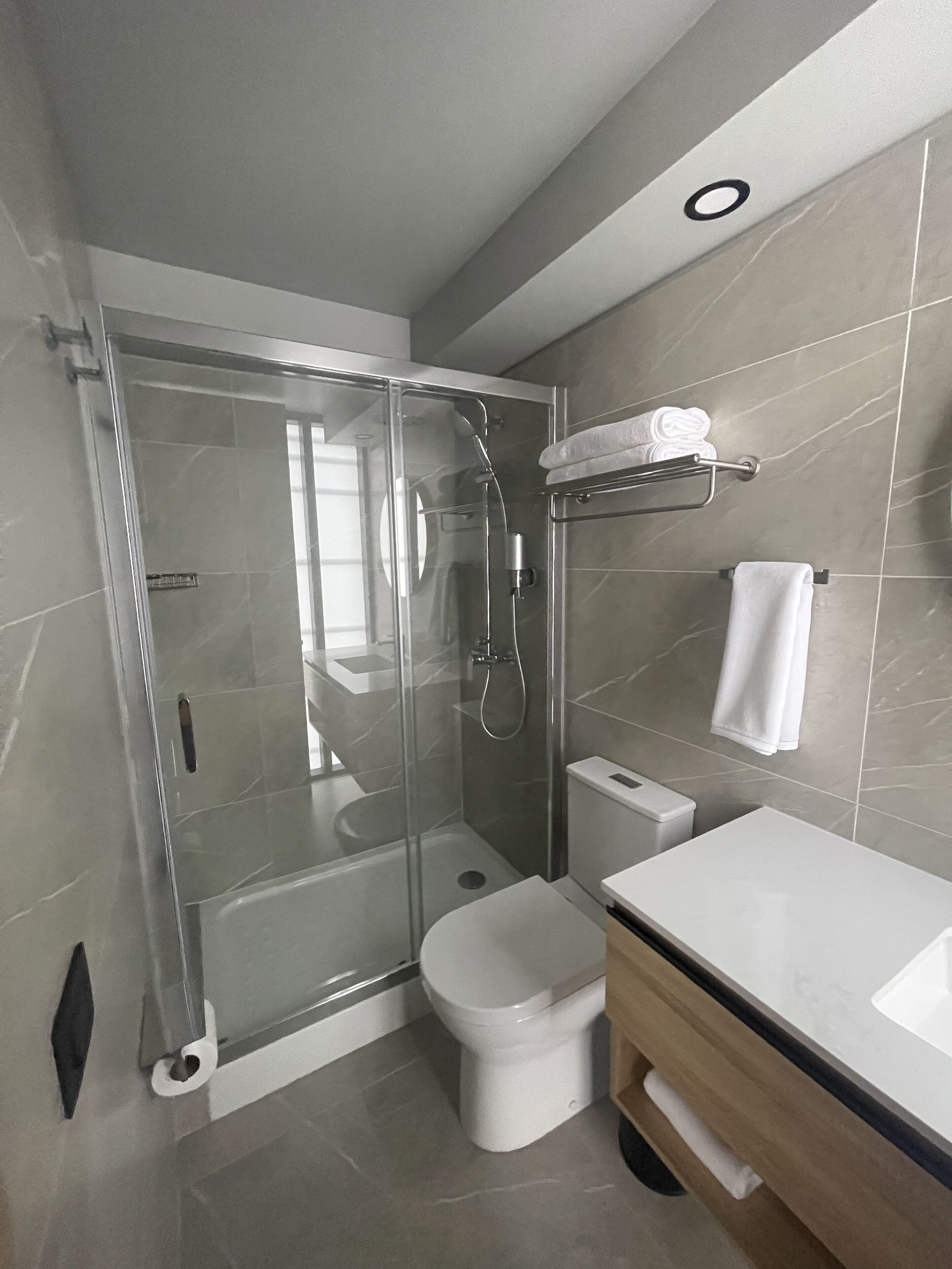 A modern bathroom with a glass-enclosed shower, a white toilet, and a vanity with a mirror.