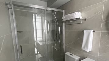 A modern bathroom with a glass-enclosed shower, a white toilet, and a vanity with a mirror.